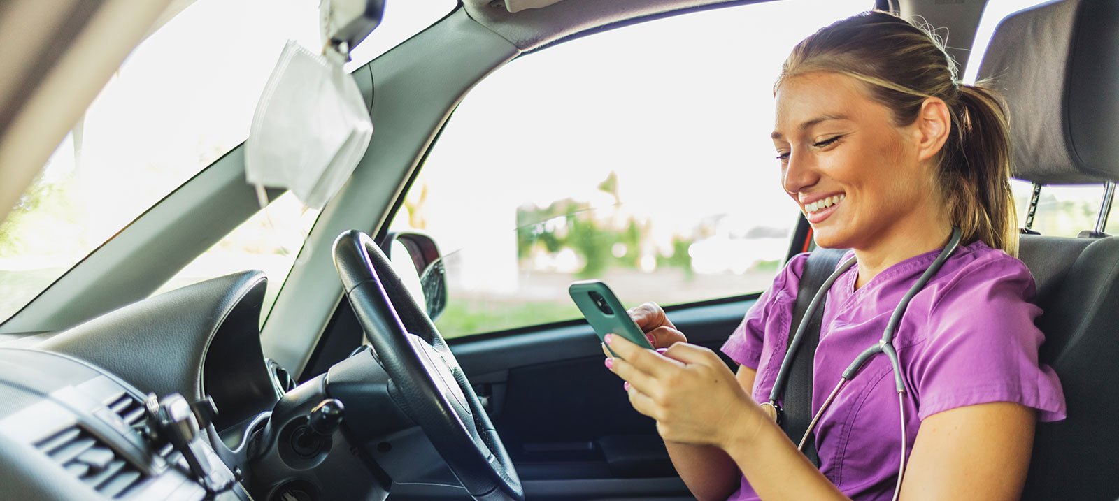 Thearpeutin mit Smartphone sitzt im Auto
